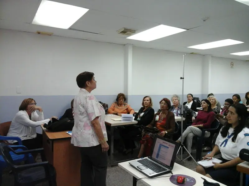 Una facilitadora conduce un taller de formación frente a un grupo de asistentes en el aula